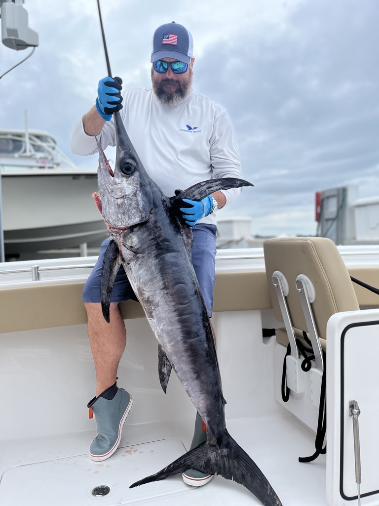 Man holding up swordfish on boat